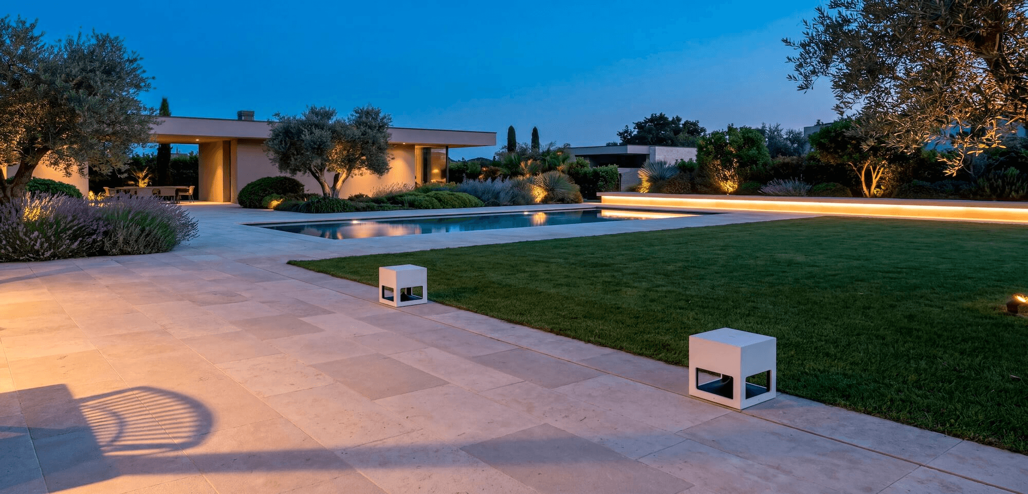 White SA117 speakers in a garden with a pool at sunset